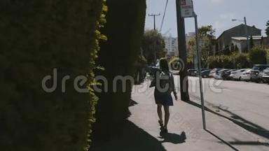 镜头跟随着快乐的年轻旅游女人，背着背包，沿着夏天的旧金山街道，触摸着绿色的栅栏。
